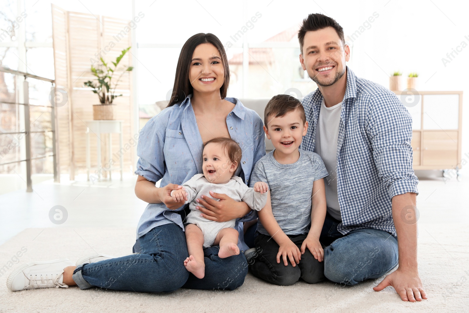 Photo of Happy couple with children sitting on floor at home. Family weekend