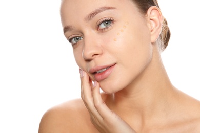 Portrait of young woman with liquid foundation on her face against white background