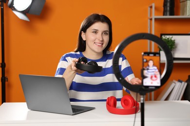 Photo of Smiling technology blogger recording video review about headphones at home