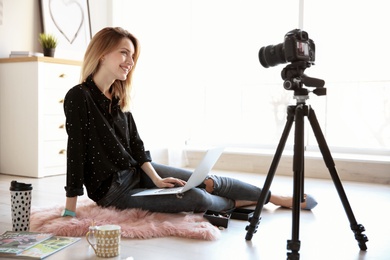 Photo of Young blogger with laptop recording video on floor at home