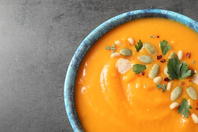 Delicious pumpkin soup in bowl on grey table, top view