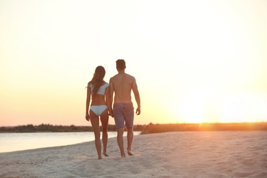 Happy young couple walking together on beach