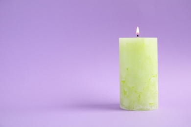 Alight wax candle on color background. Space for text