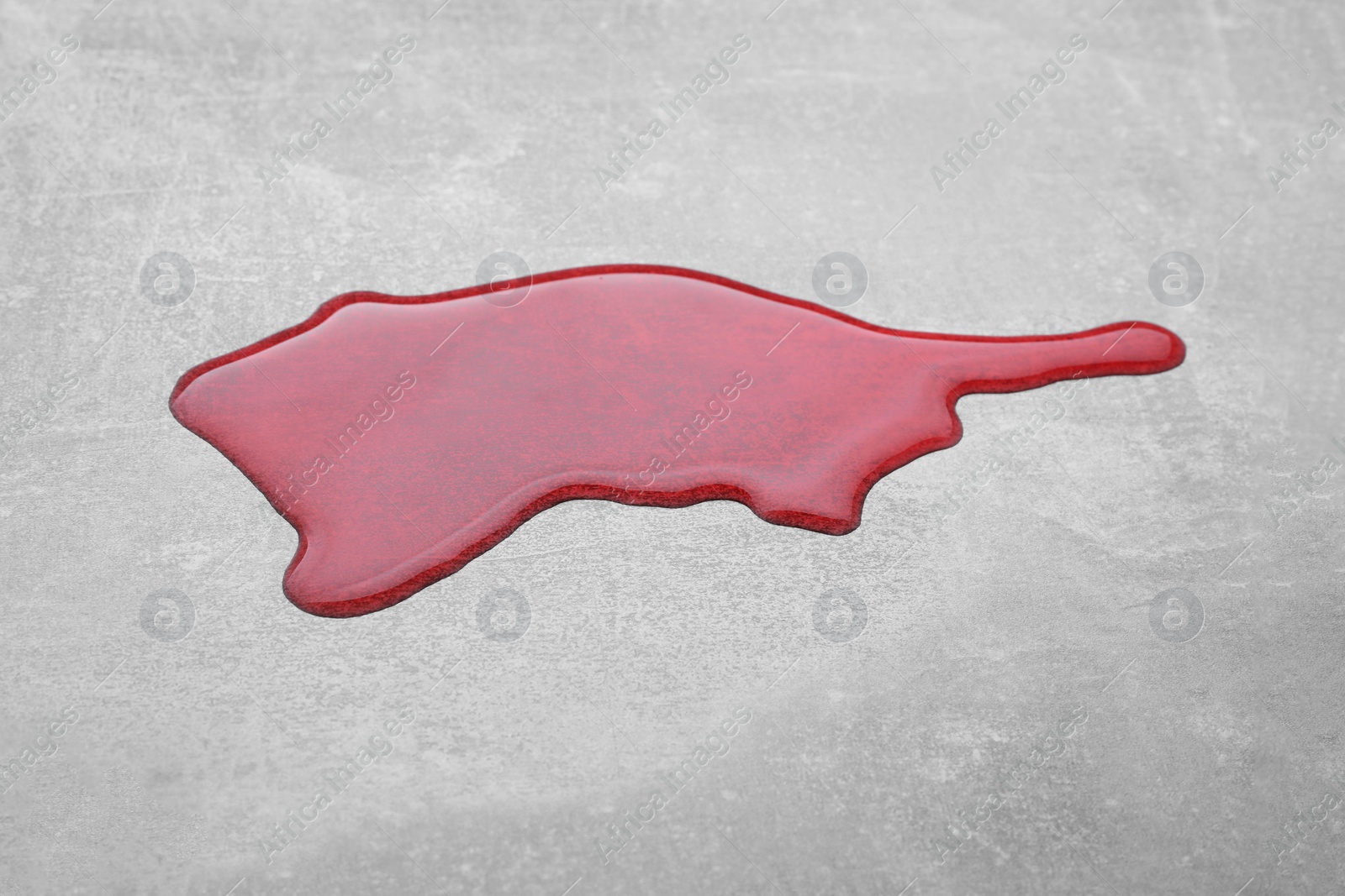 Photo of Puddle of red liquid on light grey surface
