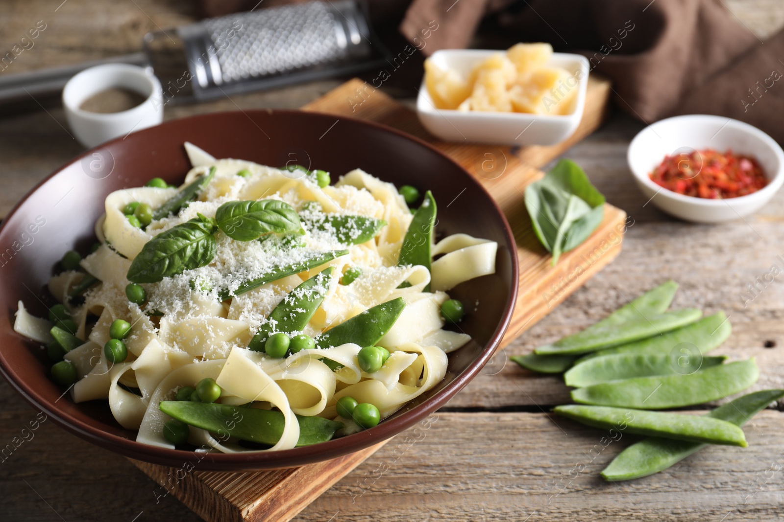 Photo of Delicious pasta with green peas, fresh basil and cheese on wooden table, closeup