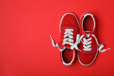 Shoes tied together on red background, flat lay with space for text. April Fool's Day
