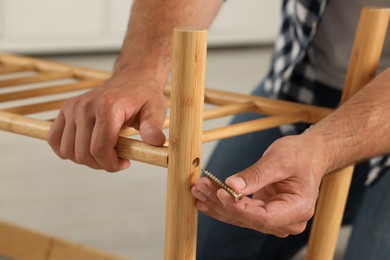 Man with self-tapping screw assembling furniture indoors, closeup