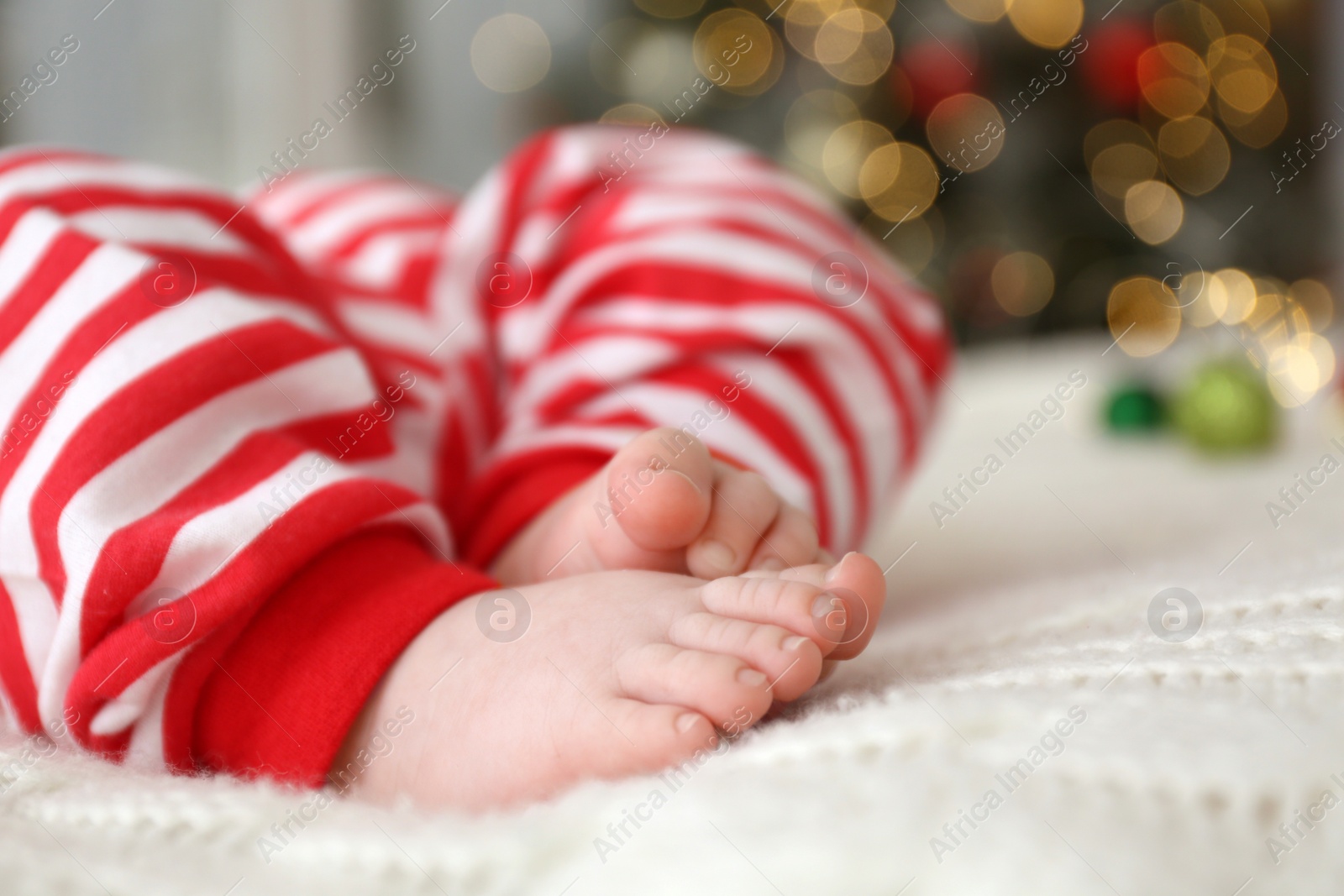 Photo of Cute little baby on blanket in room decorated for Christmas, closeup