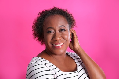 Portrait of happy African-American woman on pink background