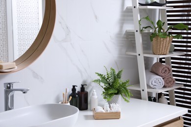 Photo of Beautiful green ferns, towels and toiletries in bathroom