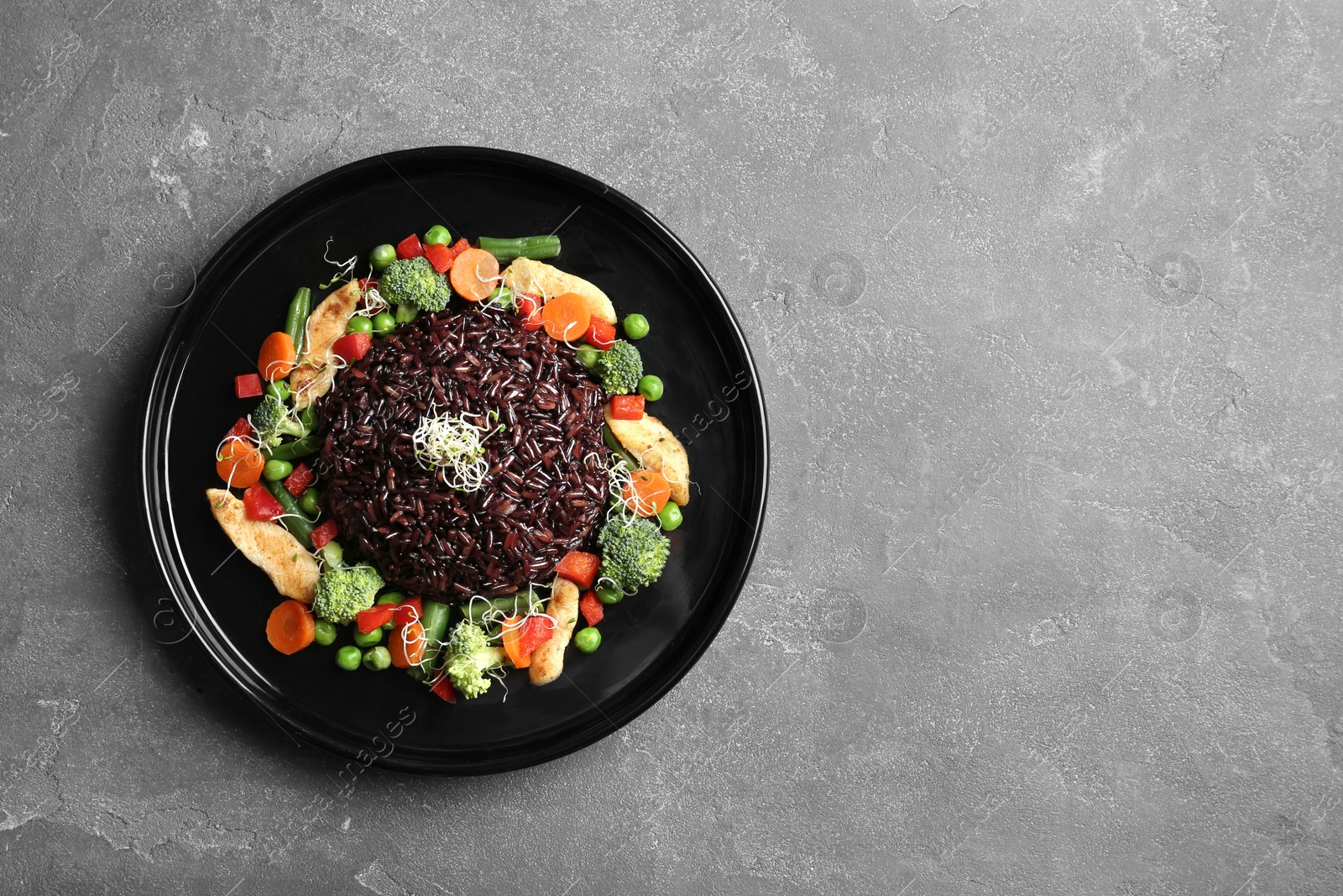 Photo of Plate with cooked brown rice on table, top view. Space for text