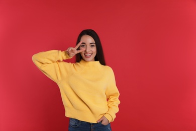 Photo of Beautiful young woman wearing yellow warm sweater on red background. Space for text