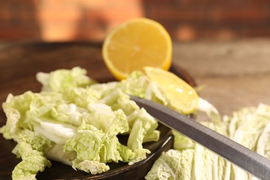 Photo of Fresh Chinese cabbage, lemon and knife on table, closeup