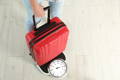 Woman weighing suitcase indoors. Space for text