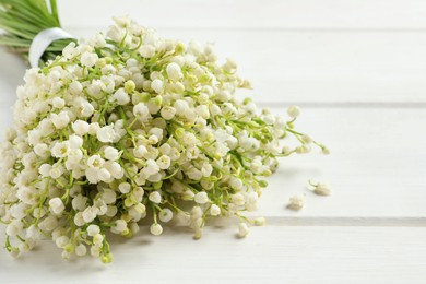 Photo of Beautiful lily of the valley bouquet on white wooden table, closeup. Space for text