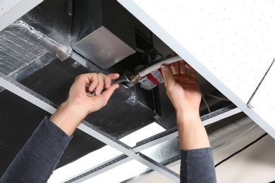 Young male technician repairing air conditioner indoors