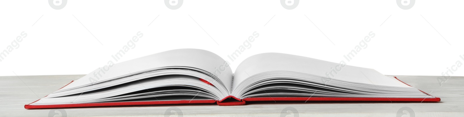 Photo of Open book with red cover on wooden table against white background