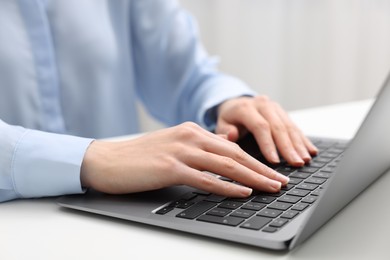 E-learning. Woman using laptop at white table indoors, closeup