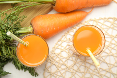 Photo of Freshly made carrot juice on white table, flat lay