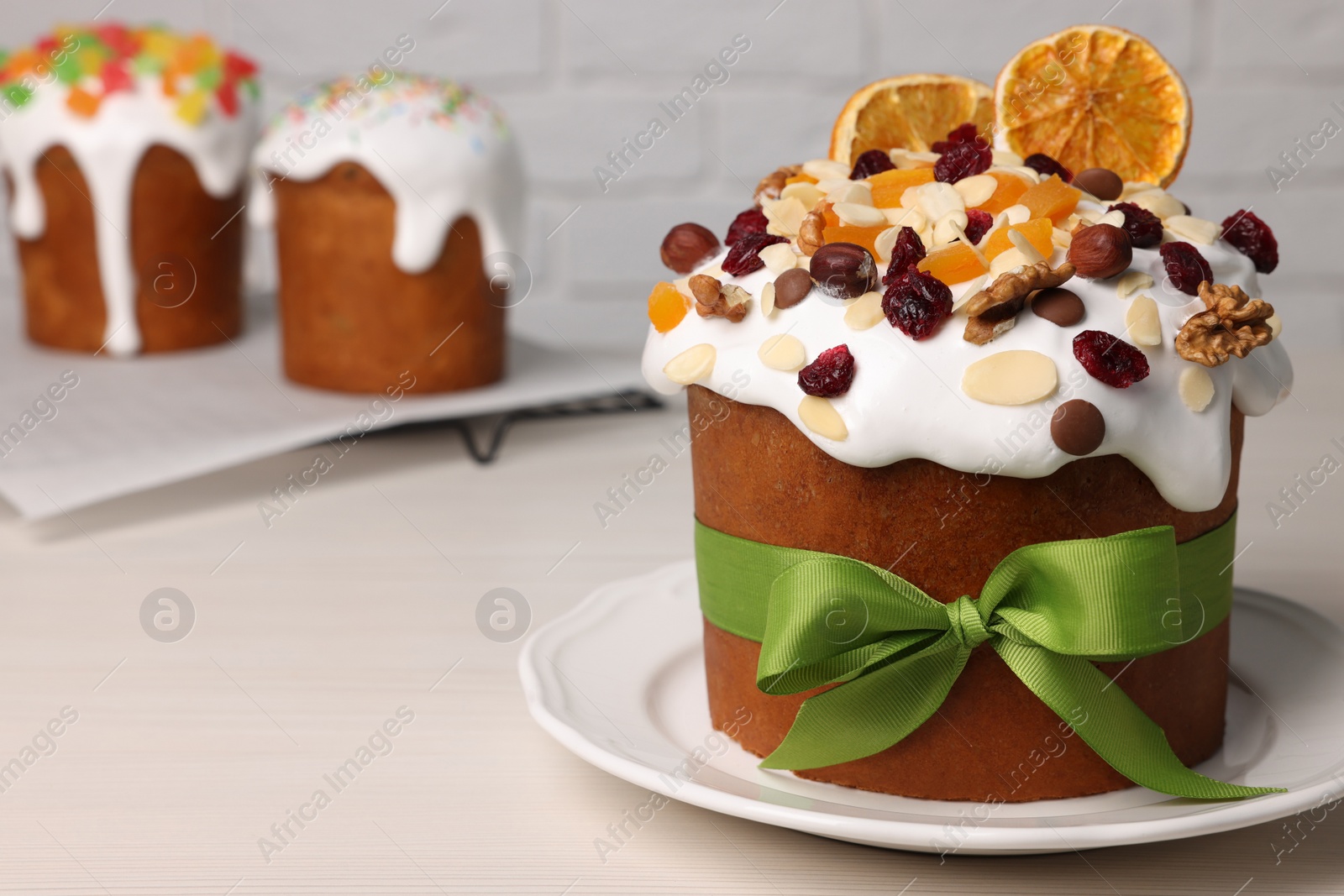 Photo of Tasty Easter cakes with dried fruits and nuts on white wooden table. Space for text