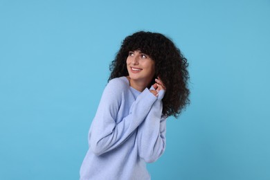 Photo of Happy young woman in stylish warm sweater on light blue background