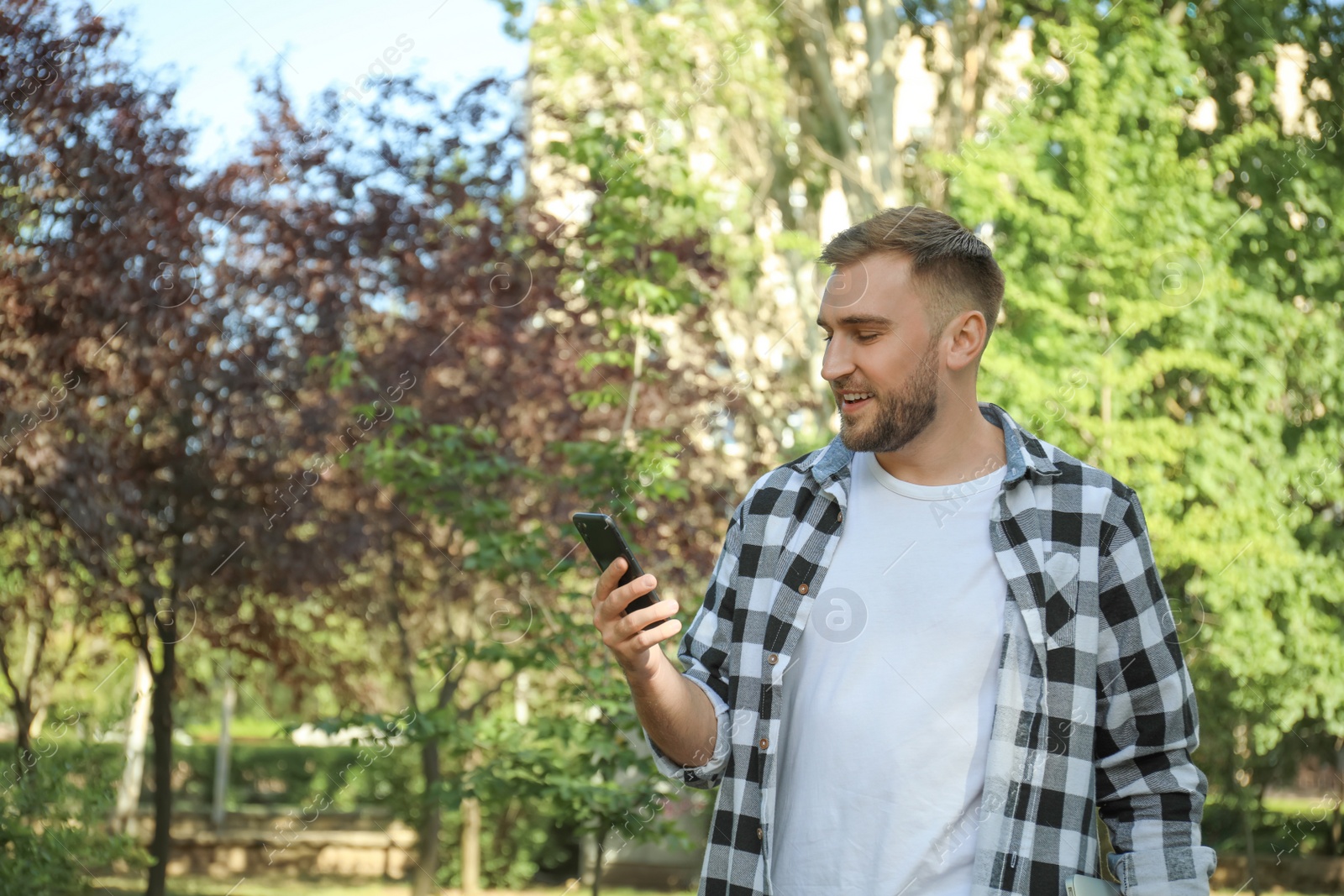 Photo of Young man with smartphone in park on summer day