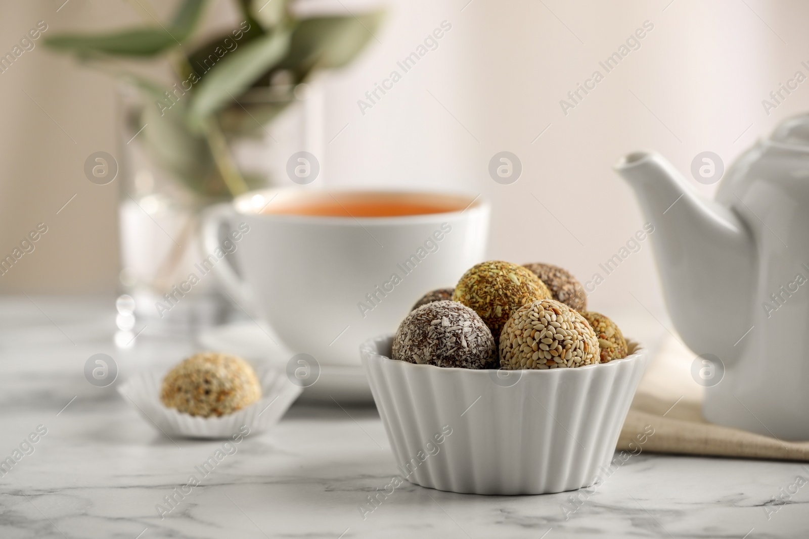 Photo of Different delicious vegan candy balls on white marble table indoors