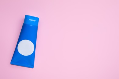 Tube of face cleansing product on pink background, top view. Space for text