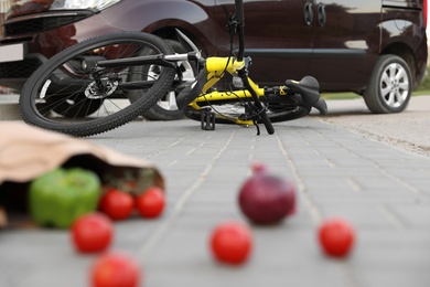 Photo of Scattered vegetables and fallen bicycle after car accident on street
