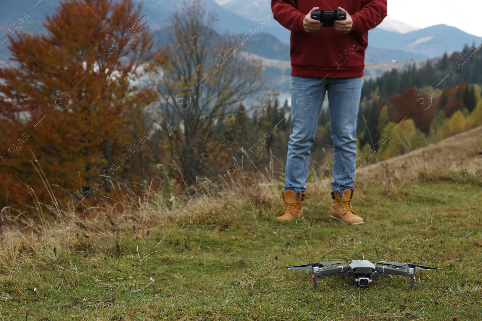 Photo of Man operating modern drone with remote control in mountains. Space for text