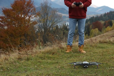 Man operating modern drone with remote control in mountains. Space for text