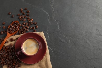 Photo of Cup of hot aromatic coffee and roasted beans on black table, flat lay. Space for text