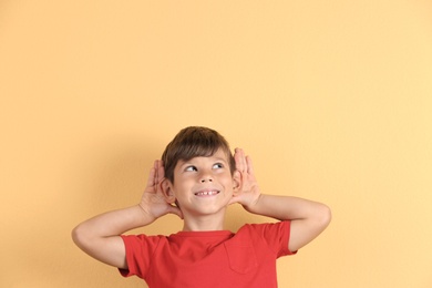 Photo of Cute little boy with hearing problem on color background. Space for text