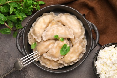 Photo of Delicious dumplings (varenyky) with cottage cheese and mint served on brown table, flat lay