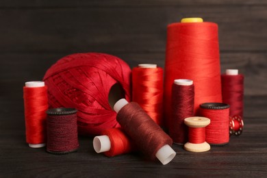 Photo of Set of color sewing threads on black wooden table