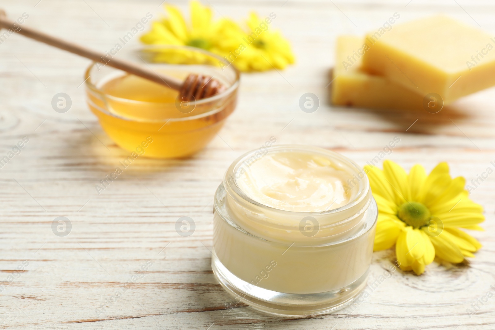 Photo of Cream with natural beeswax component on white wooden table, closeup view