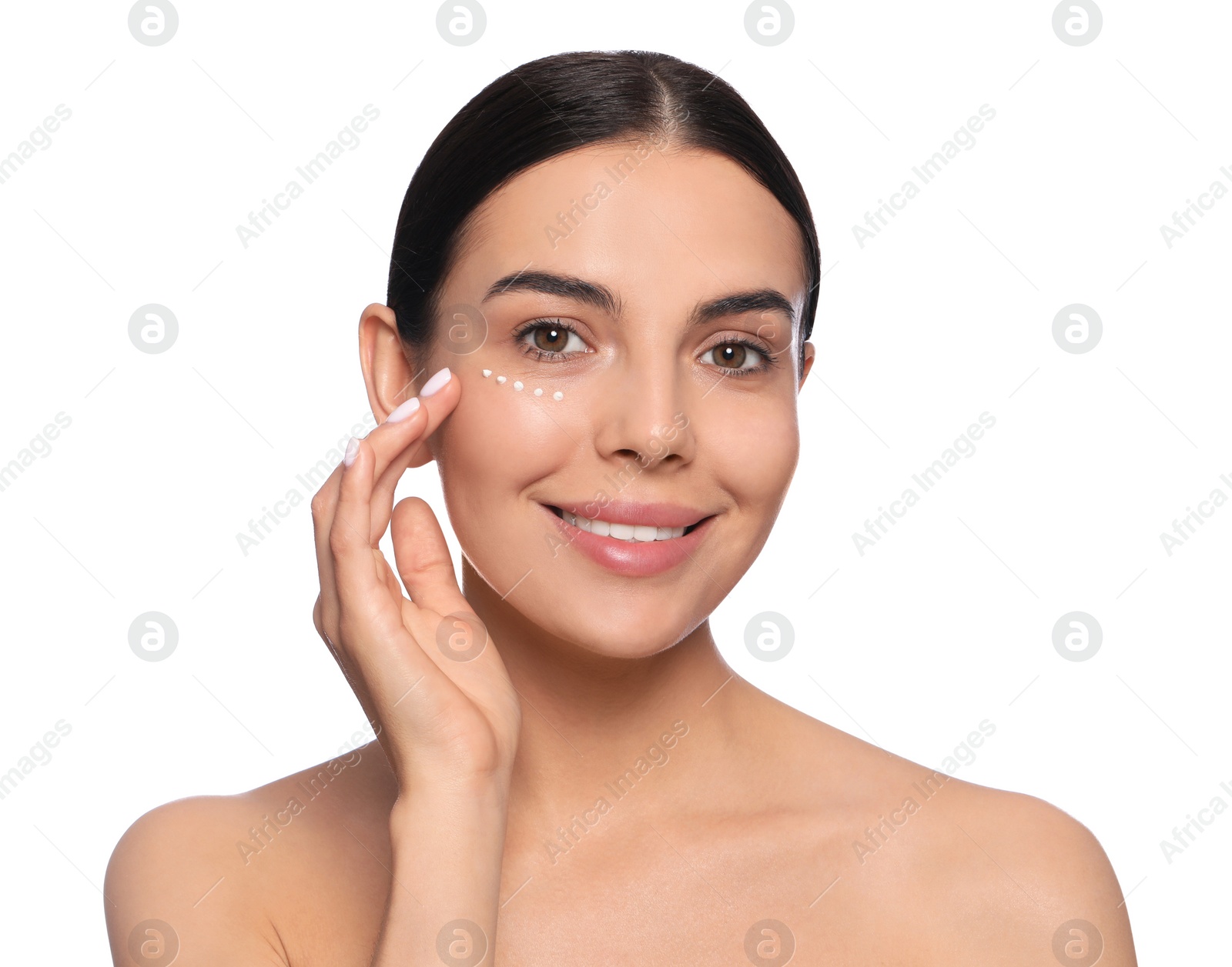 Photo of Beautiful young woman with cream on skin under eye against white background