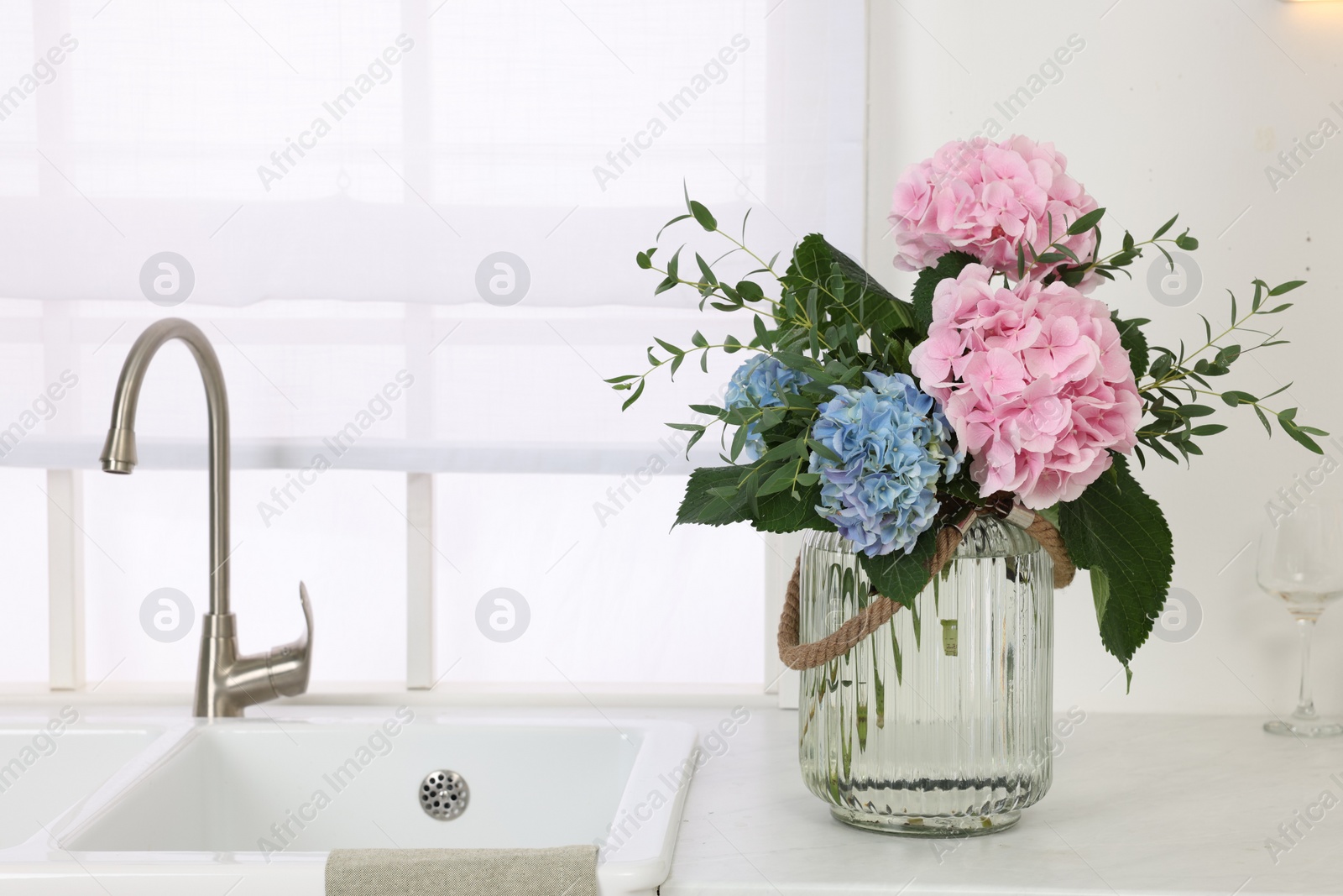 Photo of Beautiful hortensia flowers in vase on kitchen counter. Space for text