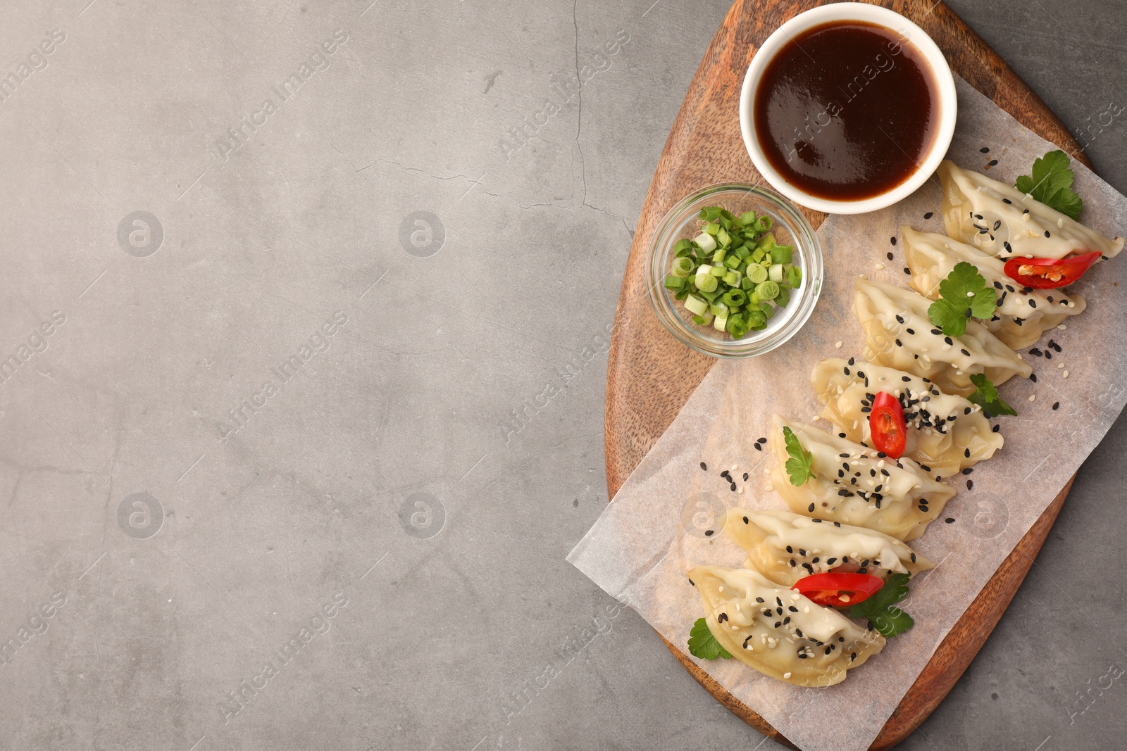 Photo of Delicious gyoza (asian dumplings) served on gray table, top view. Space for text