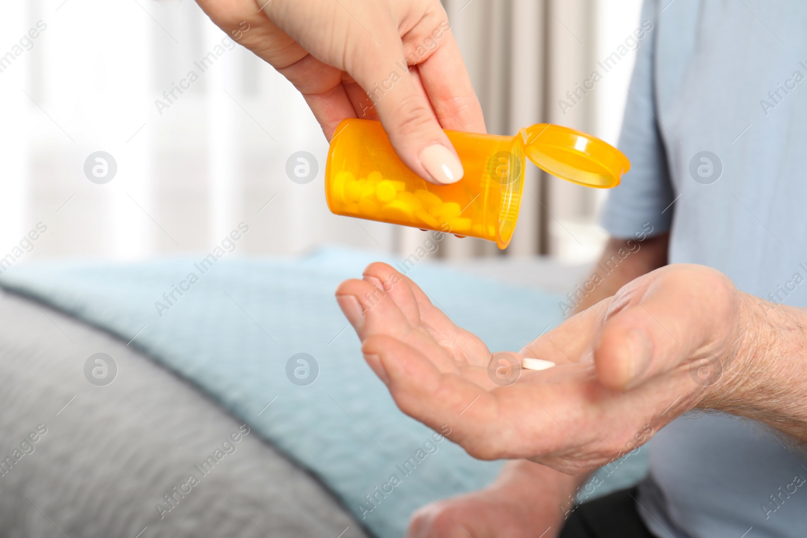 Photo of Woman giving pills to senior man indoors, closeup