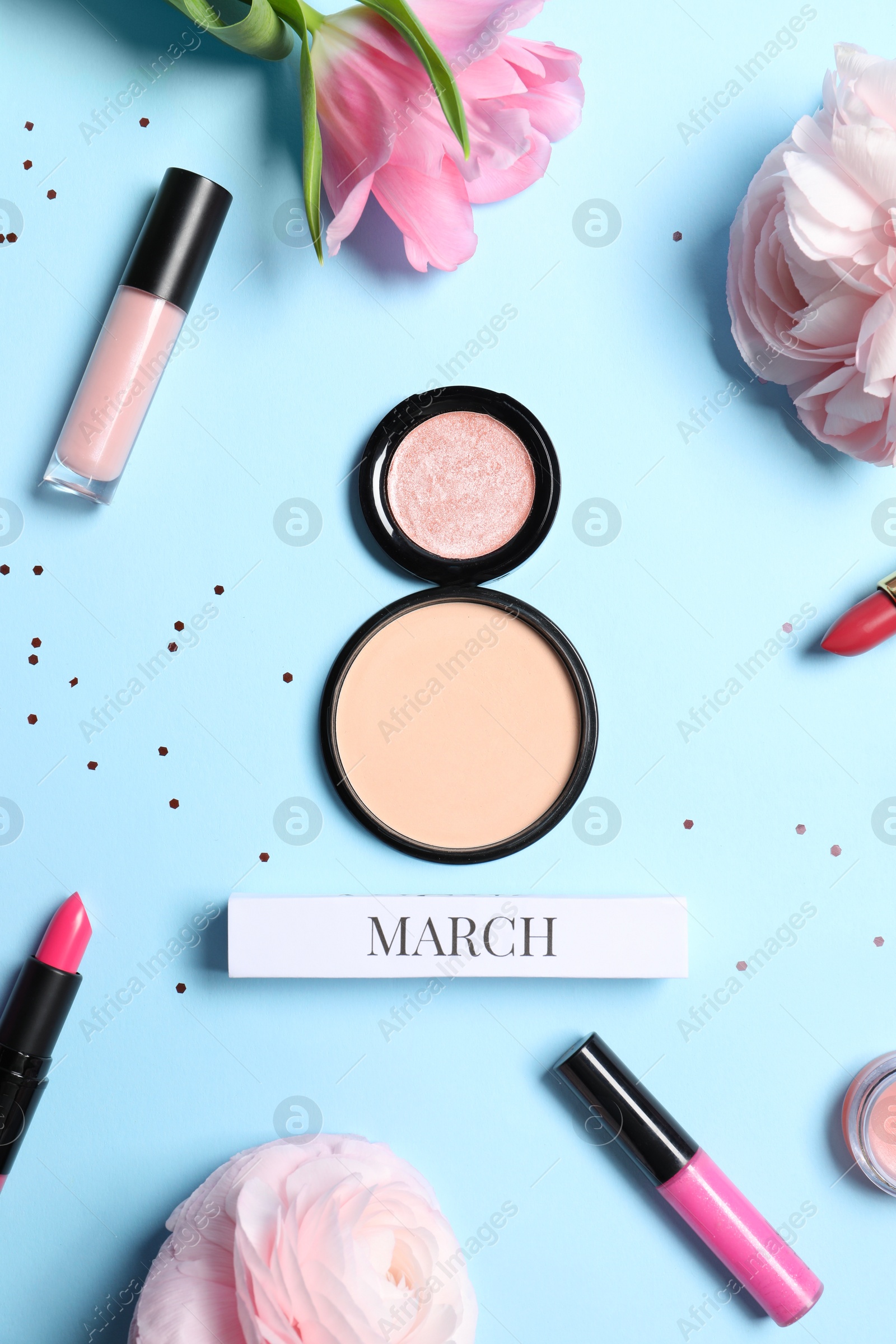 Photo of International Women's day. 8th of March made with powder, makeup products and beautiful flowers on light blue background, flat lay