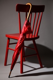 Photo of Stylish red umbrella and chair on grey background