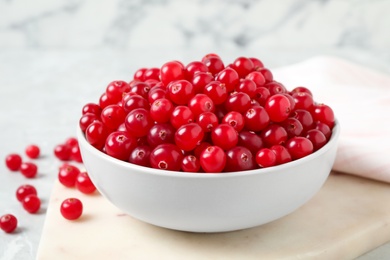 Tasty ripe cranberries on white marble board, closeup