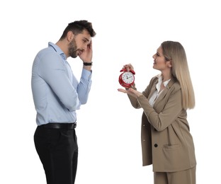 Businesswoman with alarm clock scolding employee for being late on white background