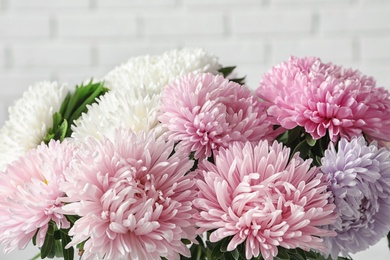 Beautiful aster flower bouquet near brick wall, closeup