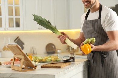 Man making dinner while watching online cooking course via tablet in kitchen, closeup