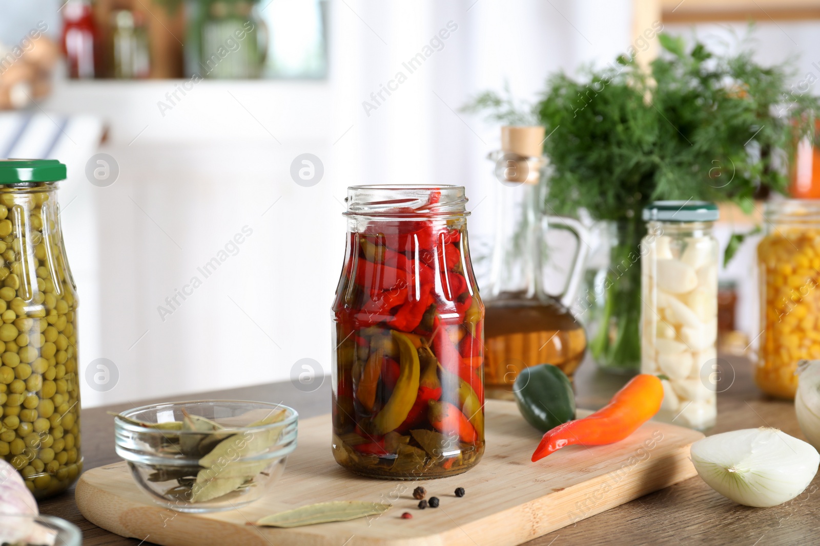 Photo of Jar with pickled chili peppers on wooden table indoors