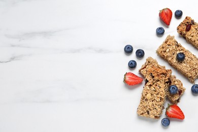 Tasty granola bars and berries on white marble table, flat lay. Space for text