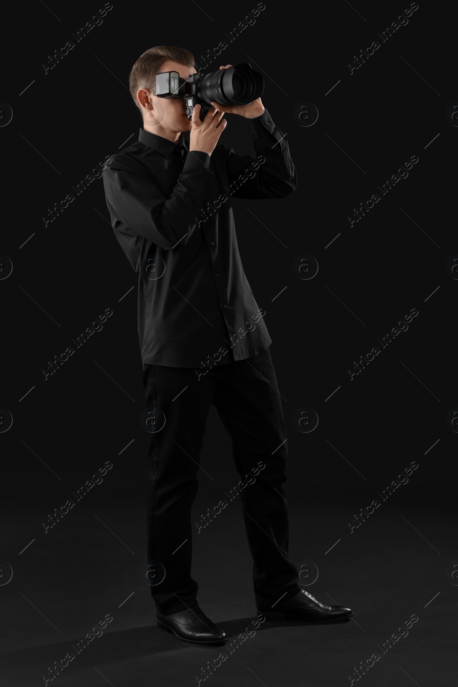 Photo of Professional photographer taking picture on black background