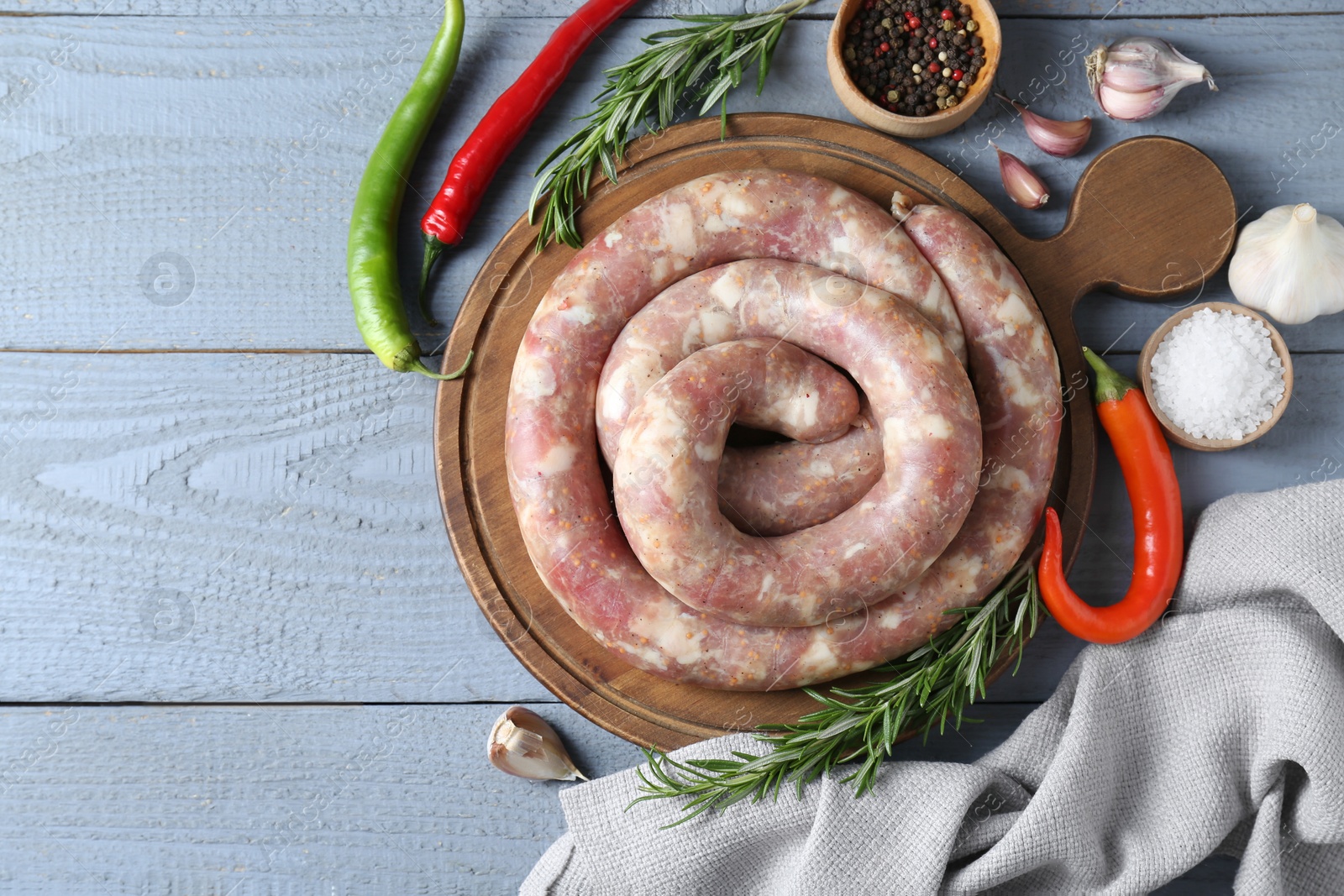 Photo of Flat lay composition with homemade sausages and products on light grey wooden table. Space for text